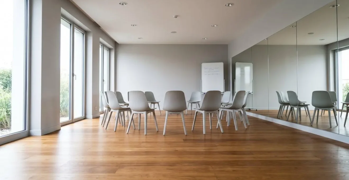 Salle de formation moderne et vide avec parquet en bois, grands miroirs muraux et lumière naturelle abondante